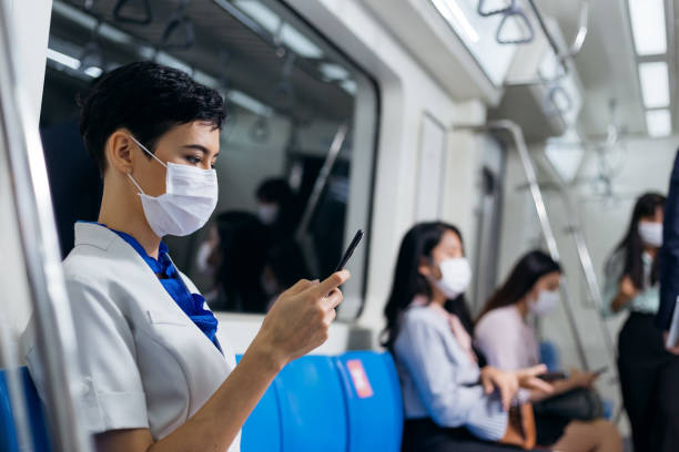 istock Portrait of woman wearing protective face mask using smartphone browsing data on the internet in subway train or metro, social distancing and new normal concept to prevent Covid-19 in public space 1273480966