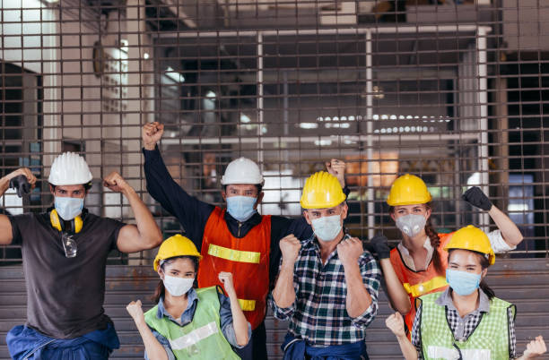 工場が建設現場で再開した後に祝う保護フェイスマスクを身に着けている産業労働者の幸せなグループ。成功ビジネスチームワーク企業の業界の人々。新しい通常の作業コンセプト - action activity sport closed ストックフォトと画像