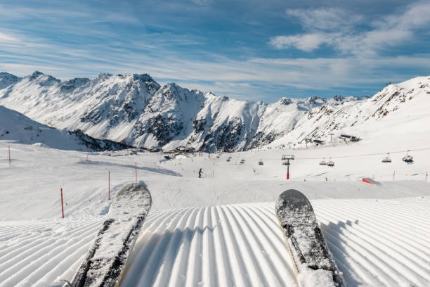 panorama-sicht skifahrerbeine auf downhill starten gerade aus geraden reihen reihen frisch präparierte skipiste auf heller tagesblauer himmelshintergrund. schneebedeckte berglandschaft europa winterresort - ski track stock-fotos und bilder