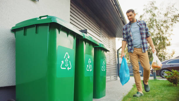 homem caucasiano está andando fora de sua casa para tirar dois sacos plásticos de lixo. um saco de lixo é classificado com resíduos biológicos de alimentos, outro é com garrafas recicláveis. salvando o meio ambiente. - places to go - fotografias e filmes do acervo