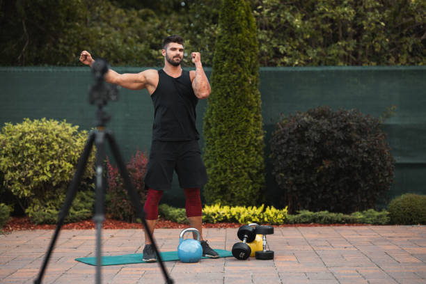 istock Male athlete doing exercise in backyard and filming vlog. 1273484715