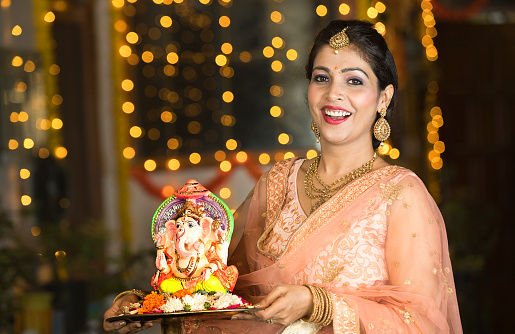 Happy woman carrying statue of Hindu god Ganesh on the occasion of Ganesh Chaturthi festival