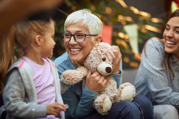 grandmother holding teddy bear, playing with her granddaughter grandmother holding teddy bear, playing with her granddaughter, smiling grandmother child baby mother stock pictures, royalty-free photos & images