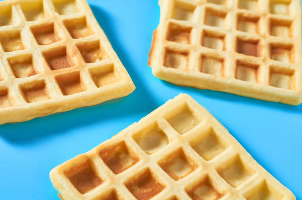 istock Scattered vanilla belgian waffles on blue background 1273486982