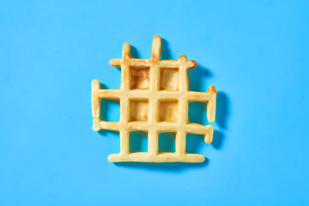 istock Broken vanilla belgian waffle on blue background. Top view 1273486997