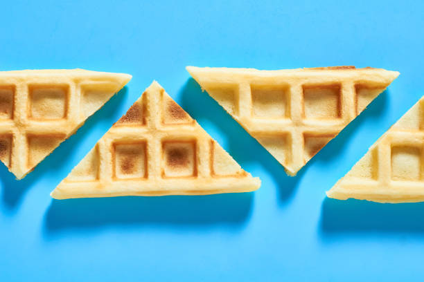 istock Row of cutted vanilla belgian waffles on blue background. Top view 1273487013