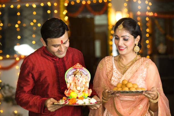 Indian couple carrying statue of Hindu god Ganesh and plate of sweet food Happy Indian couple carrying statue of Hindu god Ganesh and plate of sweet food on the occasion of festival celebration ganesh chaturthi photos stock pictures, royalty-free photos & images
