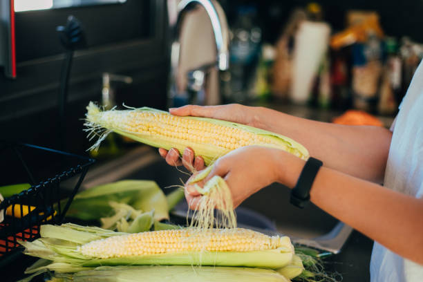 istock Woman shucking the corn before cooking in the kitchen 1273487361