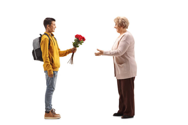 подросток-мужчина, дарить букет красных роз пожилой женщине - grandmother standing senior women senior adult стоковые фото и изображения