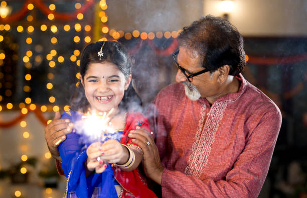 großvater und enkelin spielen mit crackern während diwali festival - indian culture family senior adult asian ethnicity stock-fotos und bilder