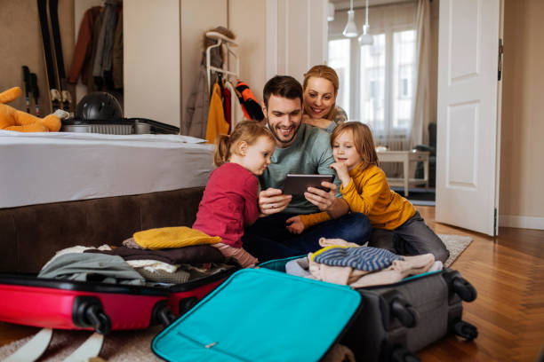 Time for a selfie! Happy family using tablet while packing for a winter vacation travel destinations family stock pictures, royalty-free photos & images