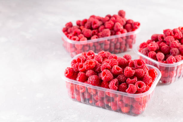 istock Fresh raspberries in a plastic tray on light background, copy space 1273493292