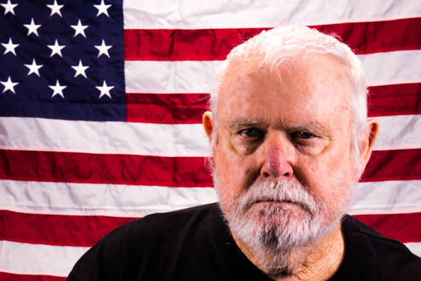 istock Old Vietnam Veteran Staring Into Camera With American Flag Background 1273494742