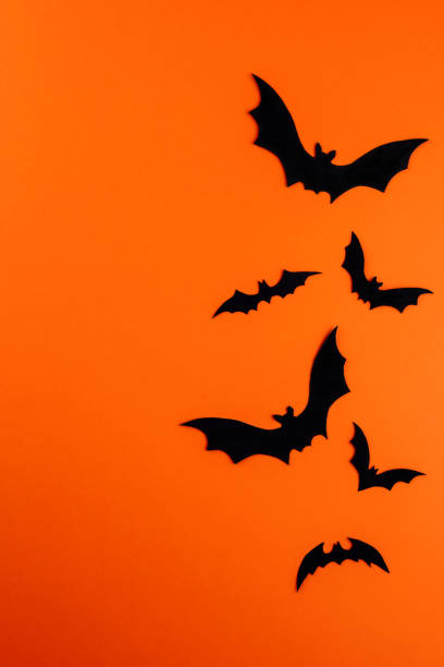 istock Few black paper bats on orange with copy space 1273495688