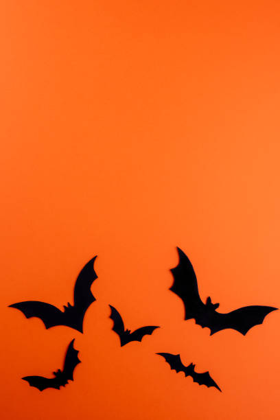 istock Black paper bats on orange with copy space 1273495703