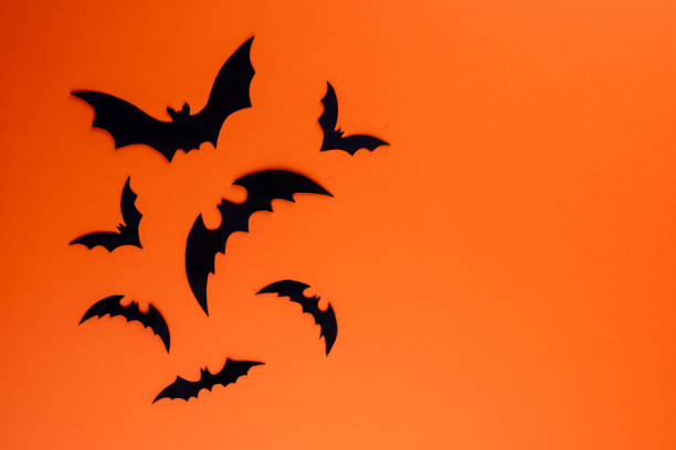 istock Group of black paper bats on orange background 1273495708