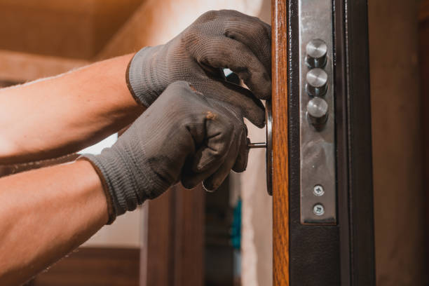istock Close-up, the carpenter installs a custom lock in the front metal door, using a drill and hammer and other tools. 1273497774