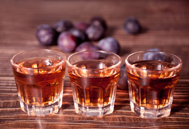 plum vodka or brandy with fresh plums on the wooden table. - slivovitz imagens e fotografias de stock