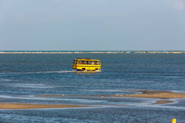 A yellow bus in the sea Rameshwaram, Tamil Nadu, India - January 2017: A yellow mini bus crossing shallow waters of the sea to reach the island of Dhanushkodi from Rameshwaram. bay of bengal stock pictures, royalty-free photos & images