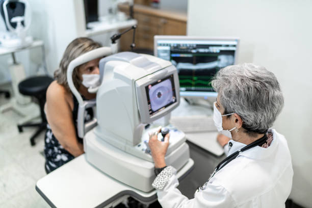 optometrista examinando los ojos del paciente - looking eyesight optometrist focus fotografías e imágenes de stock