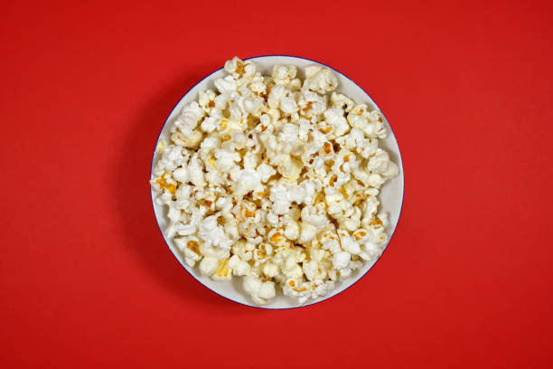 istock Popcorn in a plate on a red paper background. Close-up, top view. 1273520719