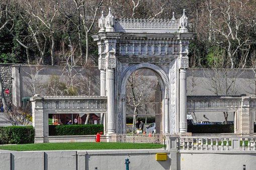 View from a boat floating on the Strait of Bosphorus of people walking next to a Gate in the Dolmabahce Palace located in the Besiktas district at Istanbul city, Turkey.