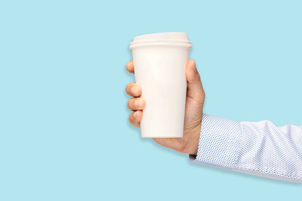 istock Man holding out a paper cup of coffee on blue background 1273531277