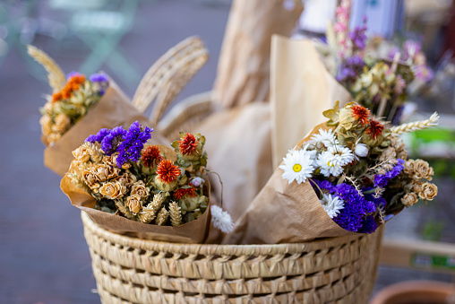 Basket with beautiful autumn bouquet of dry flowers, wrapped in the paper