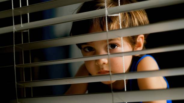 istock pensive little boy peeking through a window at night 1273540394