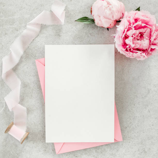 istock Mockup invitation, blank paper greeting card, pink envelope and peonies on gray stone table. Flower background. Flat lay, top view 1273540571