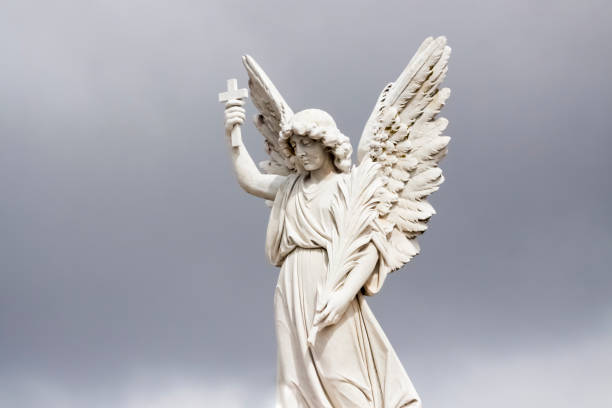 istock Angel, old statue of angle with cross, grey sky background with copy space 1273540777