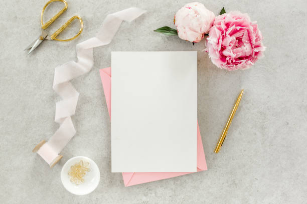 istock Mockup invitation, blank paper greeting card, pink envelope and peonies on gray stone table. Flower background. Flat lay, top view 1273544968