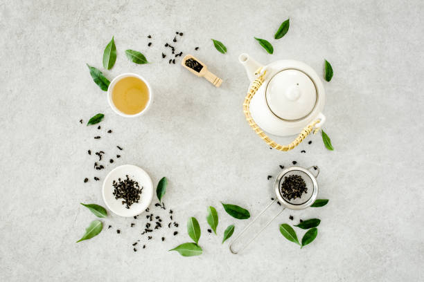 istock Herbal tea with two white tea cups and teapot, with green tea leaves. Flat lay, top view. Tea concept 1273547101