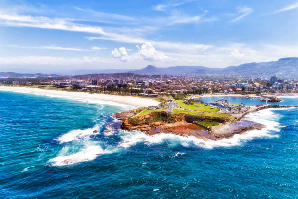 D Wollong Cape Lhouse Day from sea White lighthouse at the entrance to Wollongong harbour and marina port on coastal view from open sea - aerial. groyne stock pictures, royalty-free photos & images