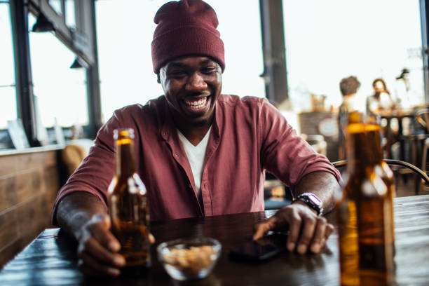 Smiling African American man enjoying beer at a bar