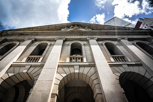 Low angle view of a stone portico with chandelier hanging. Looking up at the words Public Library engraved into the stone. Set against a perfect blue sky.