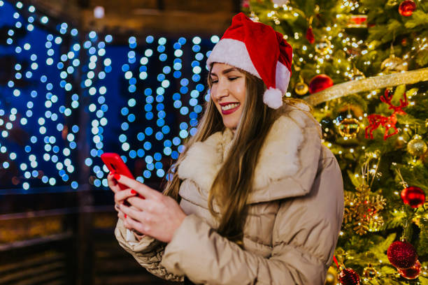 istock Woman using phone in front of a Christmas tree 1273554627