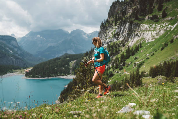 Woman hiking at lake Oeschinensee Woman hiking in the mountains by the Oeschinen lake in Berner Oberland region in central Switzerland.  Hiker hiking in Swiss alps in the summer. lake oeschinensee stock pictures, royalty-free photos & images