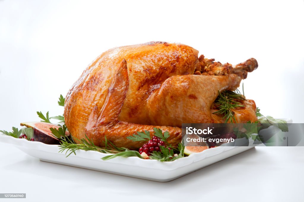 Traditional Roasted Turkey on White Garnished traditional roasted turkey, garnished with fresh figs, pomegranate, and herbs. On white background. Turkey Meat Stock Photo