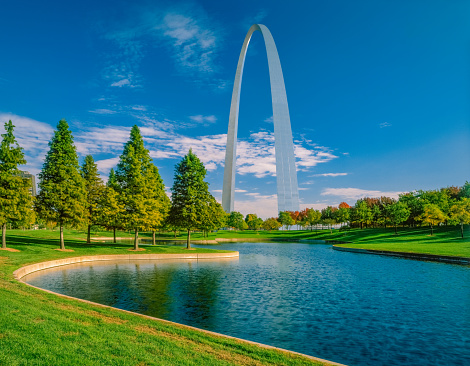 Grass, water and autumn trees surround the Gateway Arch in Saint Louis, Missouri.