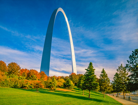 Grass, water and autumn trees surround the Gateway Arch in Saint Louis, Missouri.