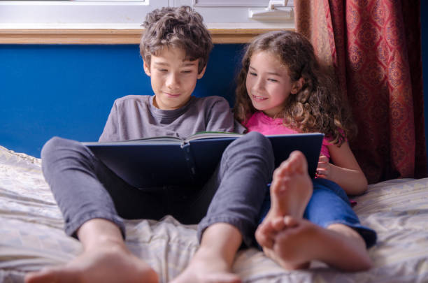 istock Young girl and boy  reading a book on her bed 1273564147