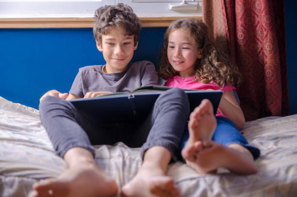 istock Young girl and boy  reading a book on her bed 1273564153