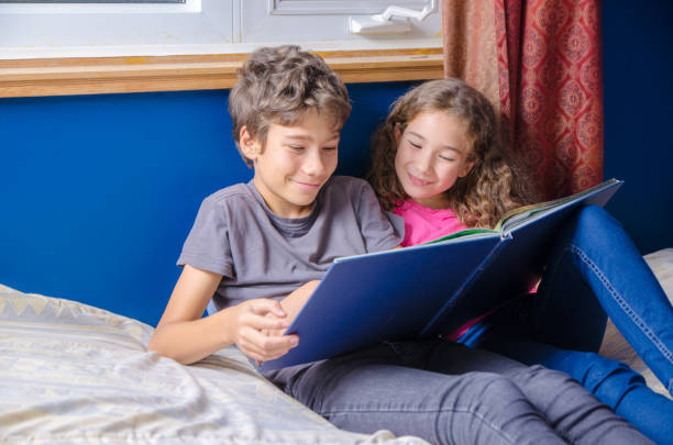 istock Young girl and boy  reading a book on her bed 1273564204