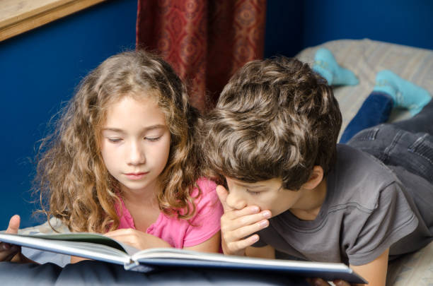 istock Young girl and boy  reading a book on her bed 1273564221