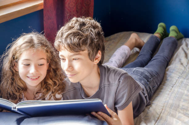 istock Young girl and boy  reading a book on her bed 1273564349