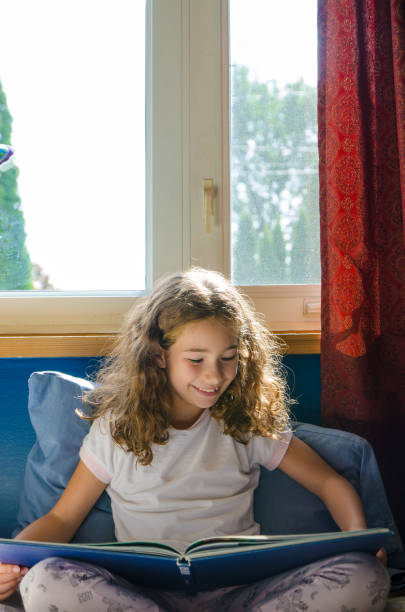 istock Young girl reading a book on her bed 1273565005