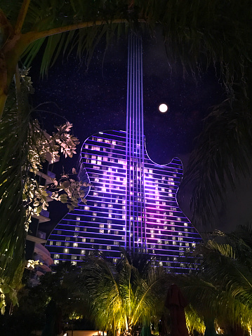 Hollywood - Fort Lauderdale, FL, USA - September 11, 2020: Colorful exterior general night view of Hard Rock Cafe & Casino guitar shaped hotel, the first guitar shaped hotel in the world. All nights the building turn on millions of lights, showing a spectacular light show on their facade.

This building is just one hour driving from Miami / Miami Beach, and two hours driving from Orlando and Disney's Theme Parks.