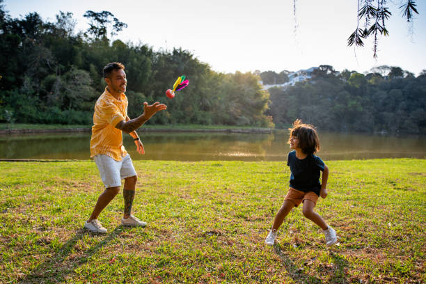 padre jugando al volante con su hijo en la naturaleza - shuttlecock fotografías e imágenes de stock