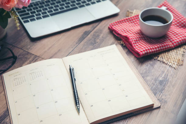 istock Calendar and Laptop for Planner to plan reminder daily appointment timetable, appointment, organization and meeting agenda of job on wooden desk, work from home. Coffee, book, computer place on table 1273572017